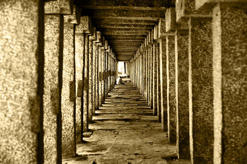 stone pillars temple repetition man sitting sepia